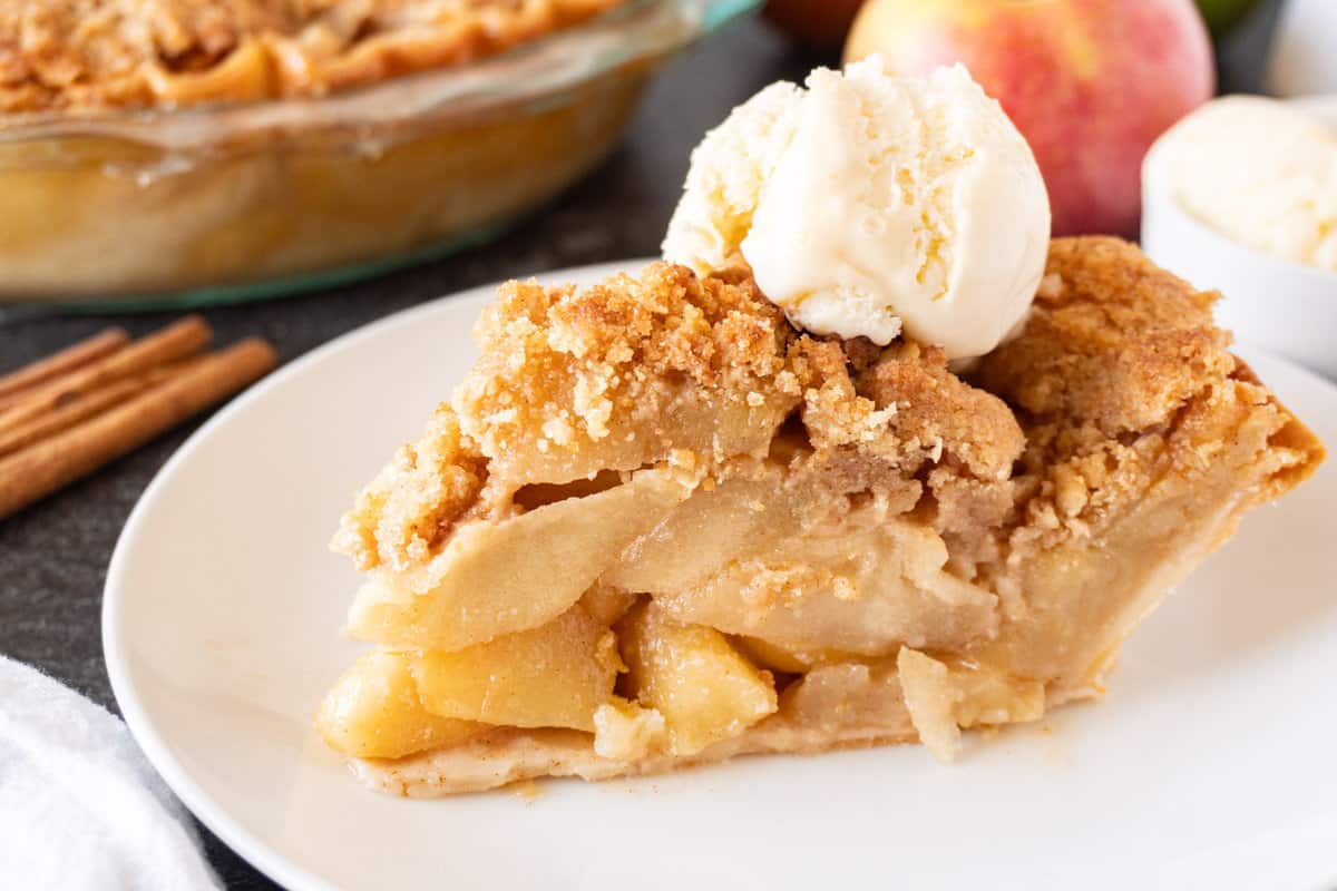 close up of slice of apple pie with ice cream scoop on top