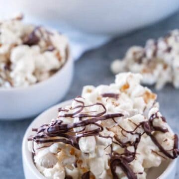 This chocolate drizzled popcorn is easy to make and super addicting! Three ingredients is all it takes to make this yummy treat! #popcorn #chocolate #whitechocolate #atablefullofjoy #party #forkids #easytomake