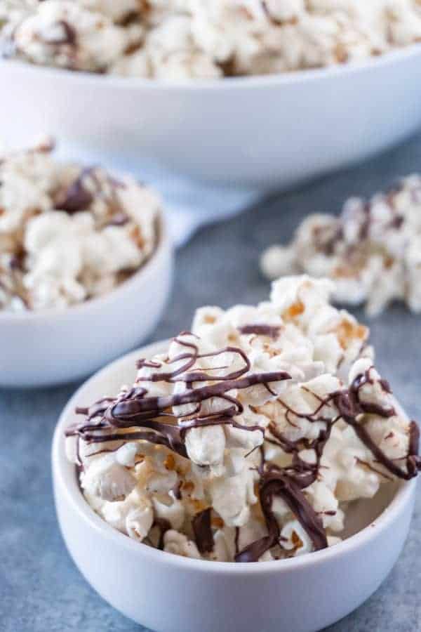 This chocolate drizzled popcorn is easy to make and super addicting! Three ingredients is all it takes to make this yummy treat! #popcorn #chocolate #whitechocolate #atablefullofjoy #party #forkids #easytomake