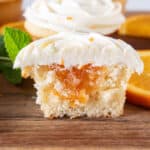 orange cupcake cut in half showing marmalade filling, sitting on wooden cutting board, featured image