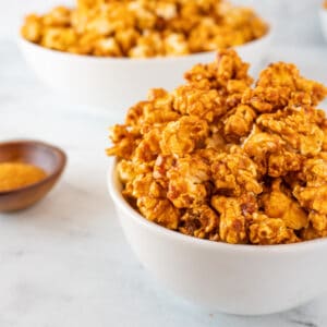 buffalo popcorn in bowl with cayenne pepper in background featured image