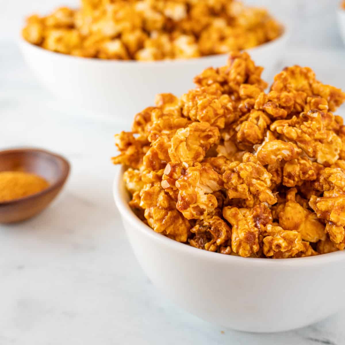 buffalo popcorn in bowl with cayenne pepper in background featured image