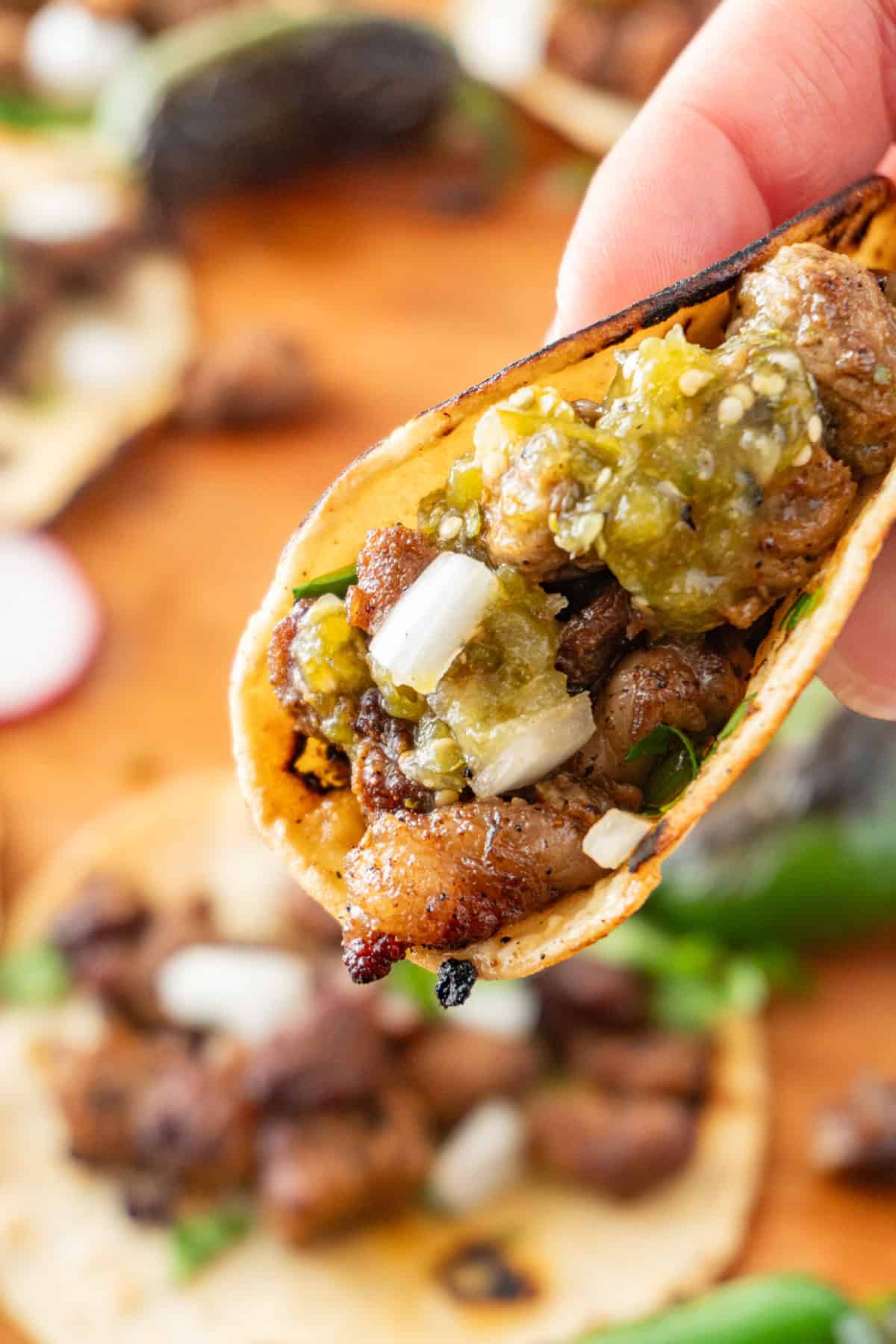 holiding a taco with green salsa