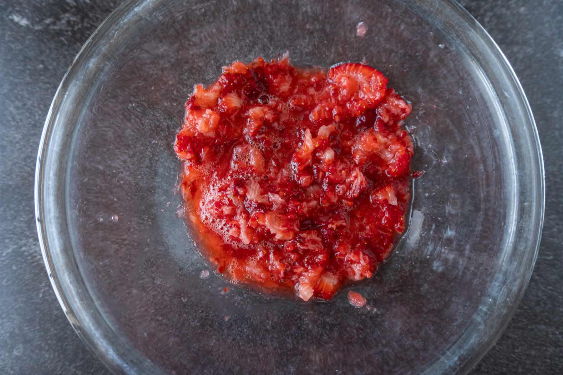 mashed strawberries in a clear glass bowl.