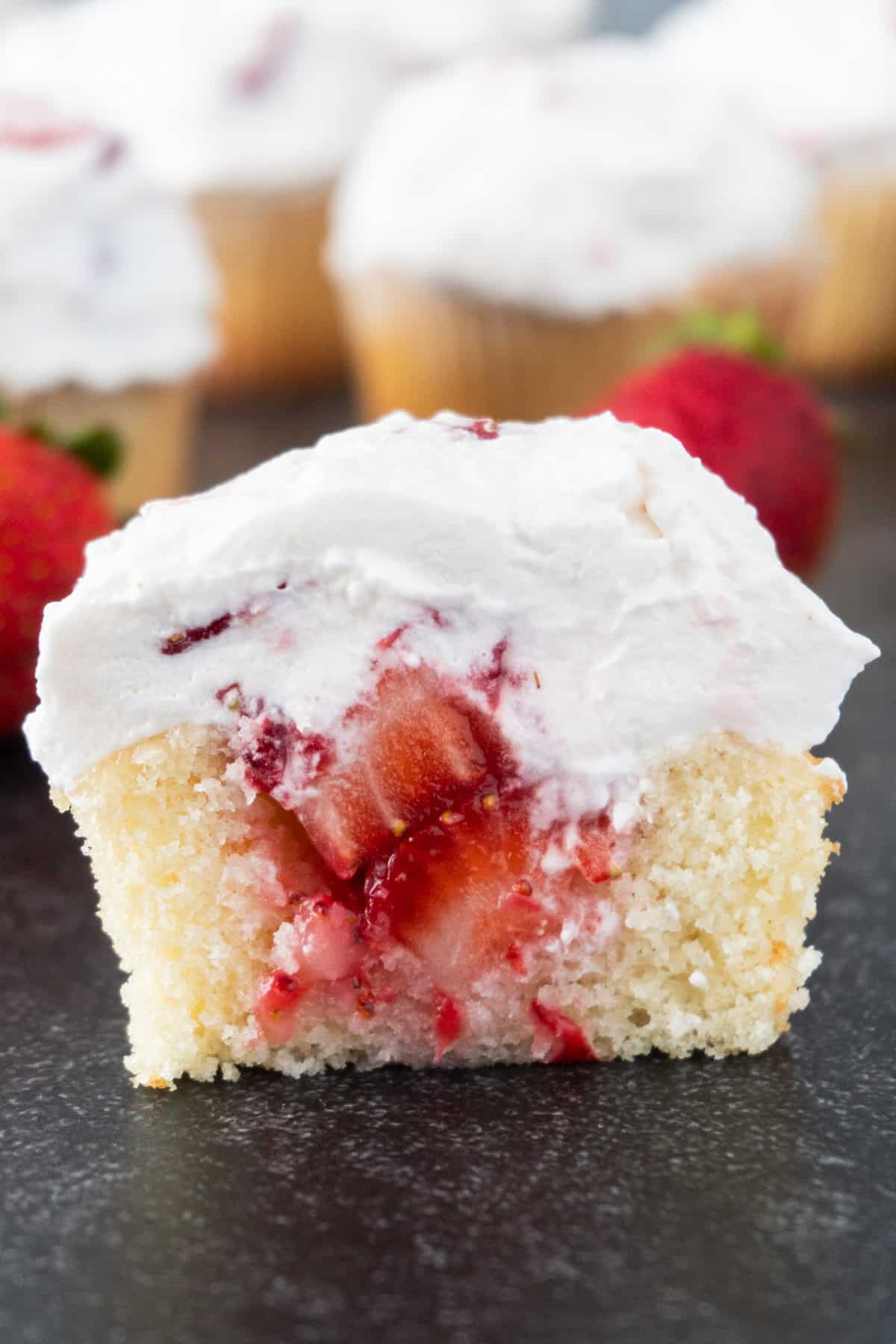 strawberry shortcake cupcake cut in half to show strawberry filling.