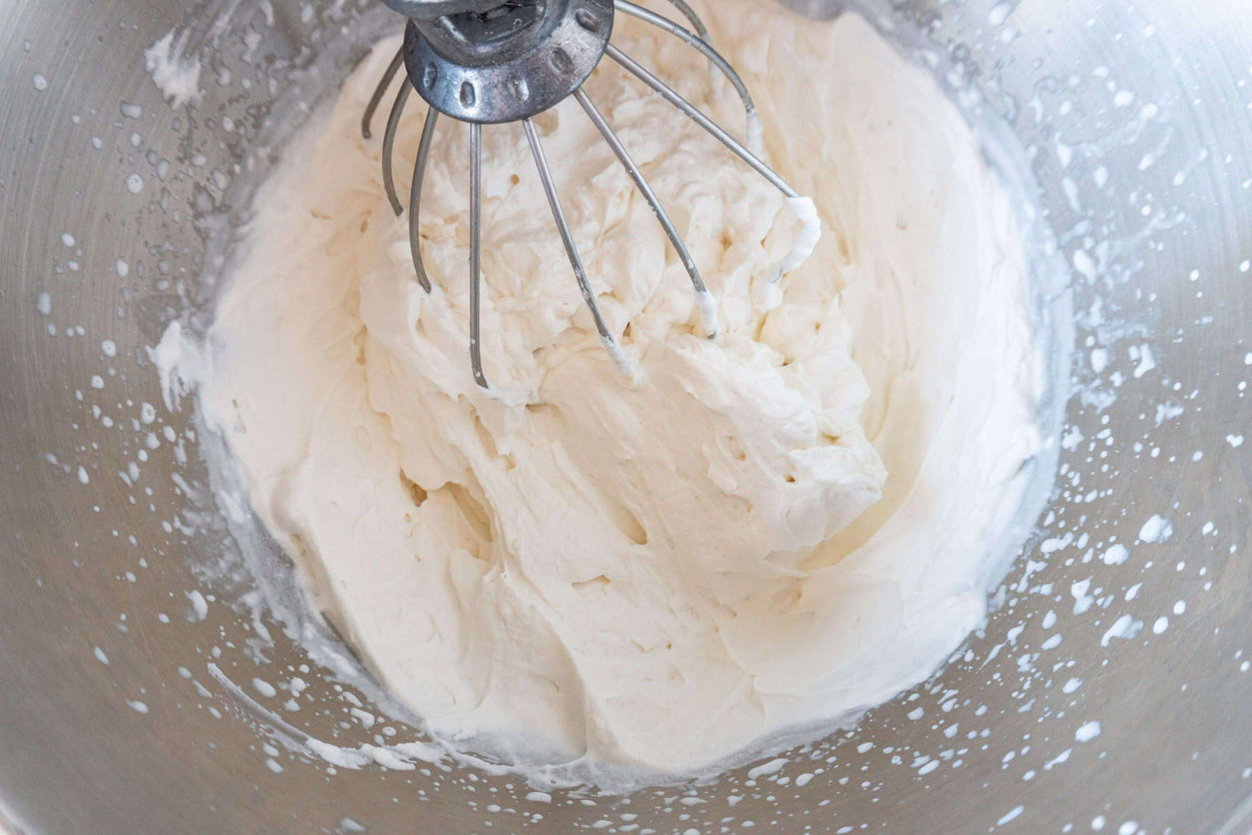 whipped cream mixed in bowl with stand mixer whisk attachment.