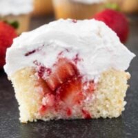 strawberry shortcake cupcake cut in half to show center filled with strawberry filling, featured image.