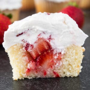 strawberry shortcake cupcake cut in half to show center filled with strawberry filling, featured image.