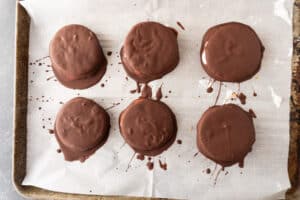 moon pies dipped in chocolate and on baking sheet.