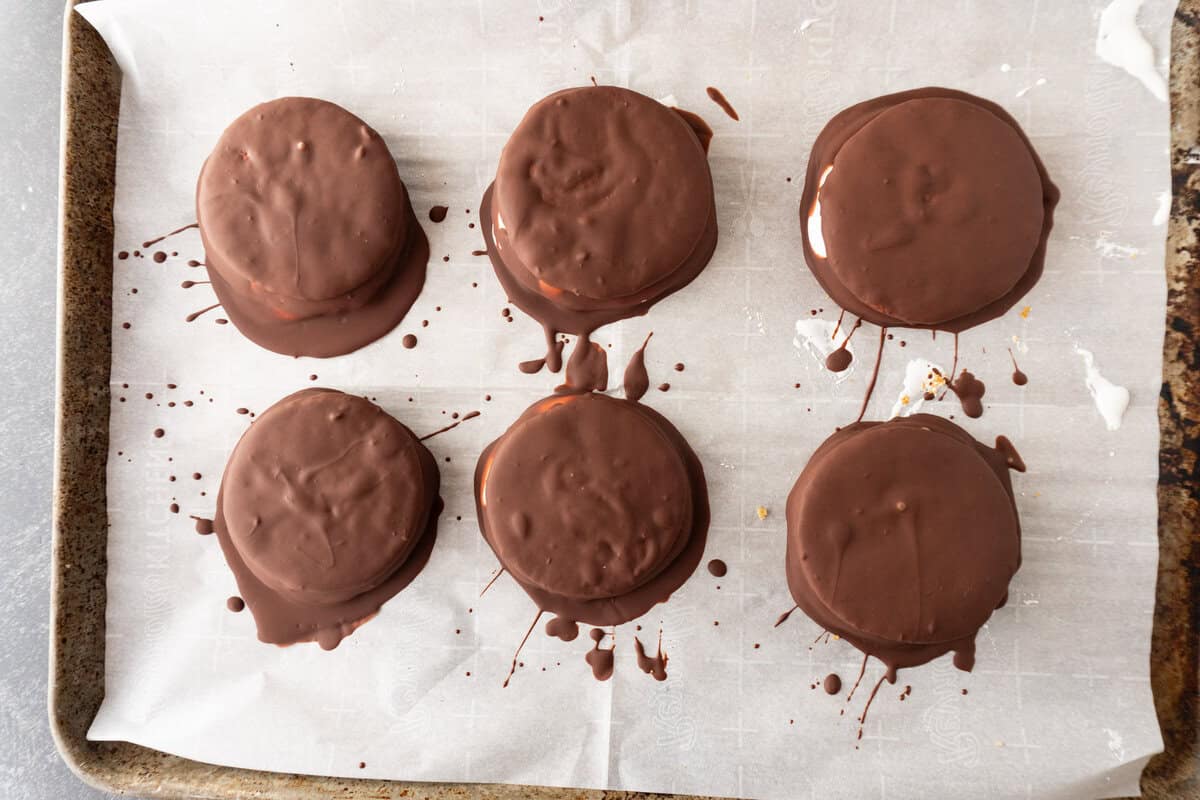 moon pies dipped in chocolate and on baking sheet.
