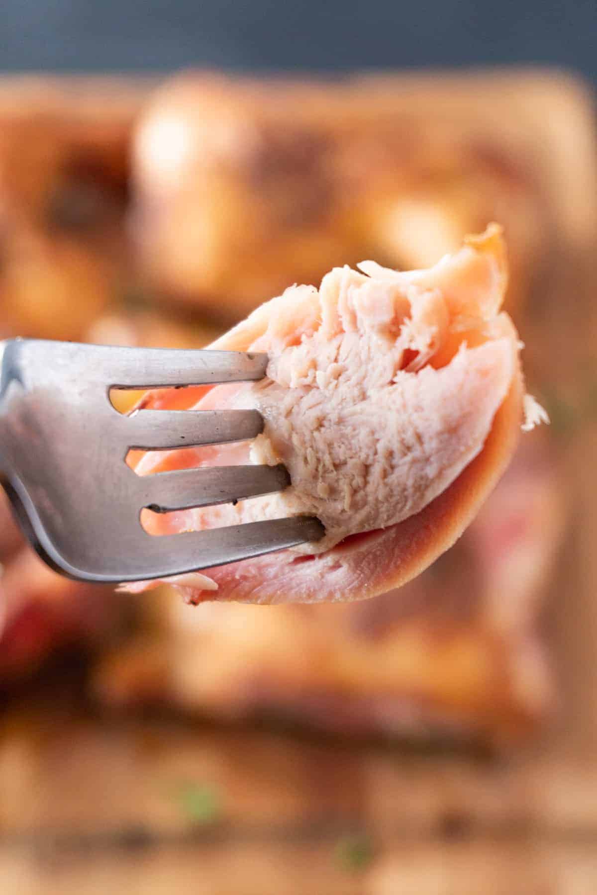 Piece of smoked chicken on fork with smoke ring