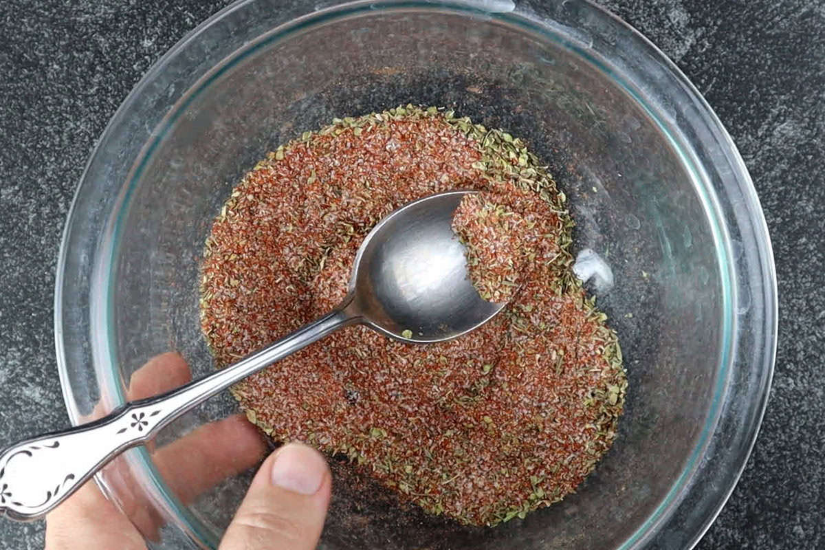 dry rub ingredients mixed in clear glass bowl with spoon.