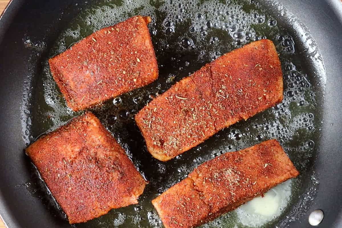 seasoned salmon filets in non stick pan.