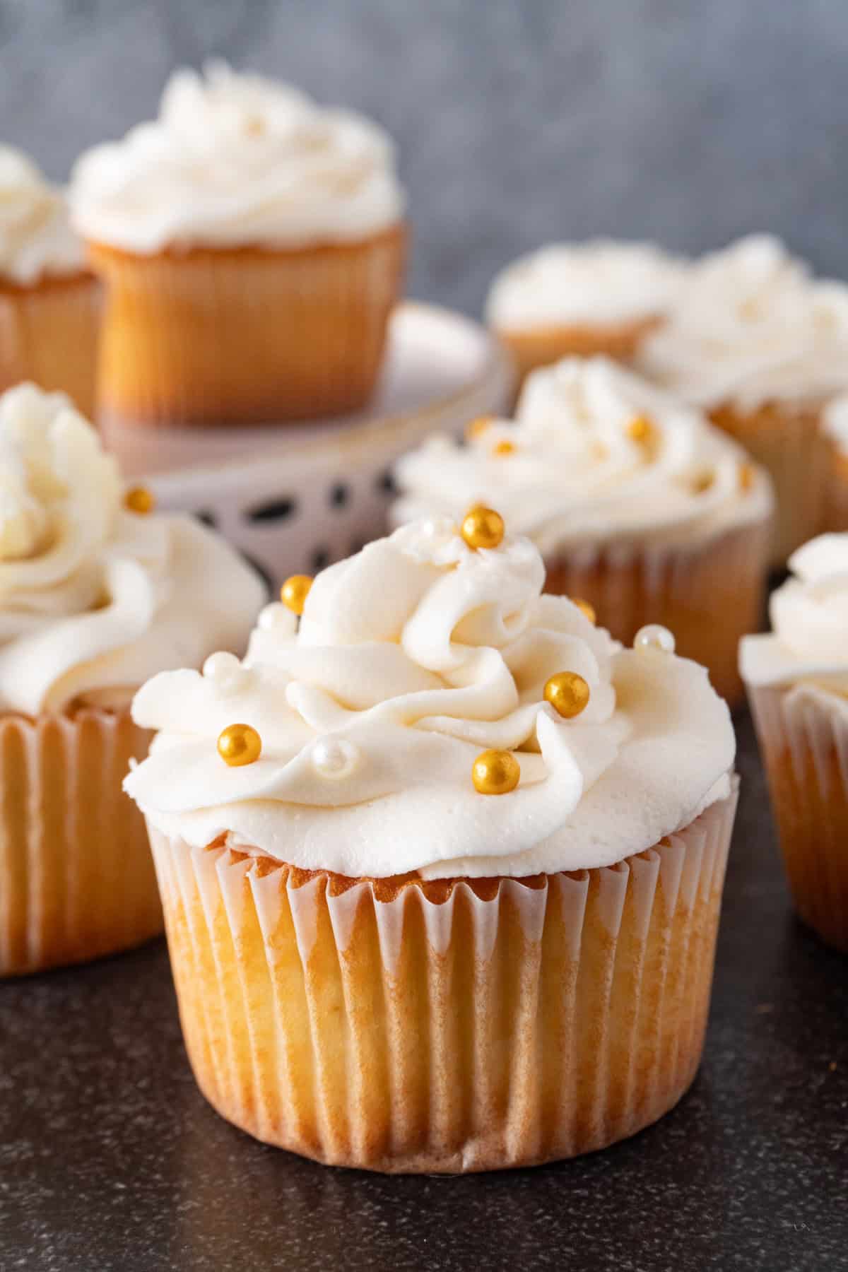White chocolate cupcakes with white chocolate frosting and gold and white sprinkles.