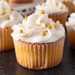 White chocolate cupcake with white chocolate frosting and gold and white sprinkles, featured image.