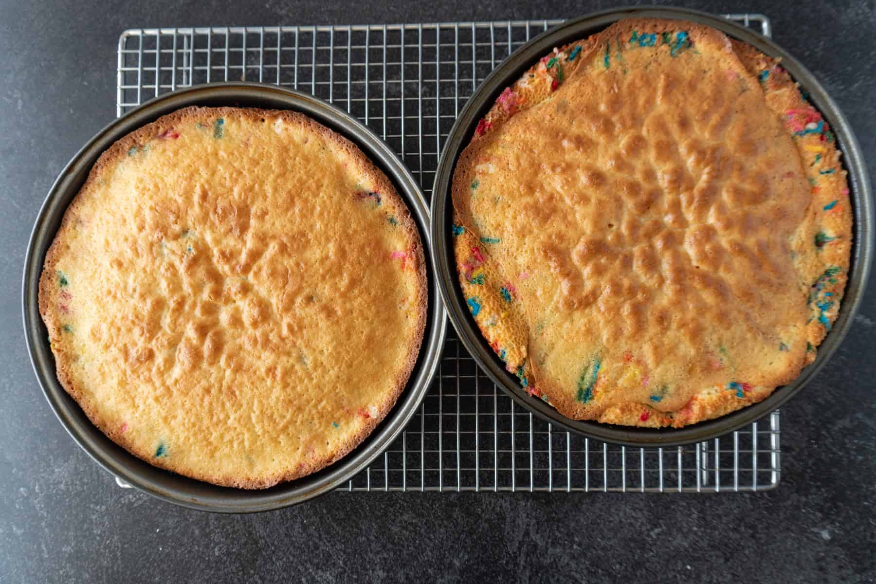 Birthday cakes baked in two round cake pans sitting on cooling rack.