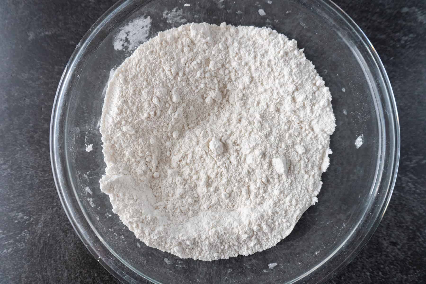 dry ingredient flour mixture for cake mixed in a clear glass bowl.