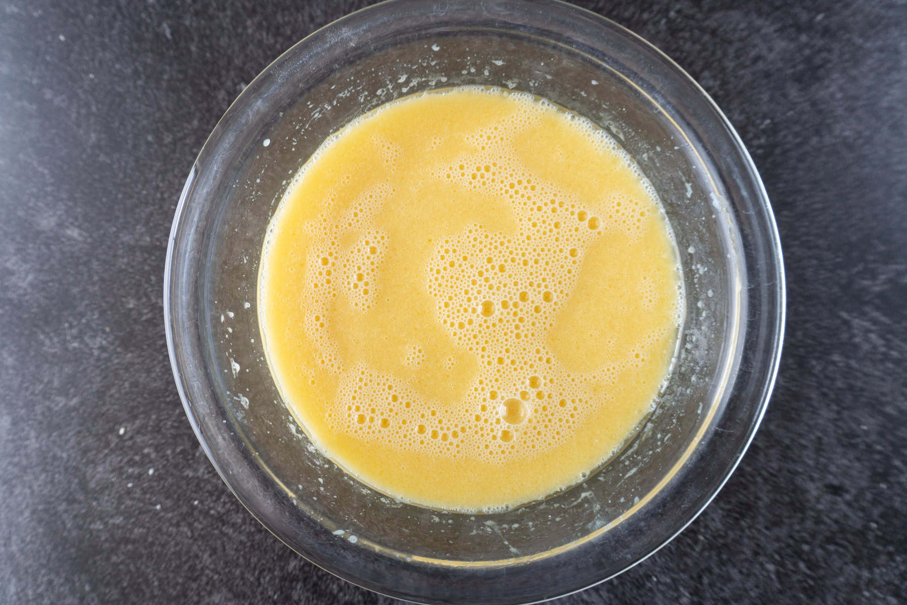 Buttermilk, eggs and butter mixture for cake in clear glass bowl.