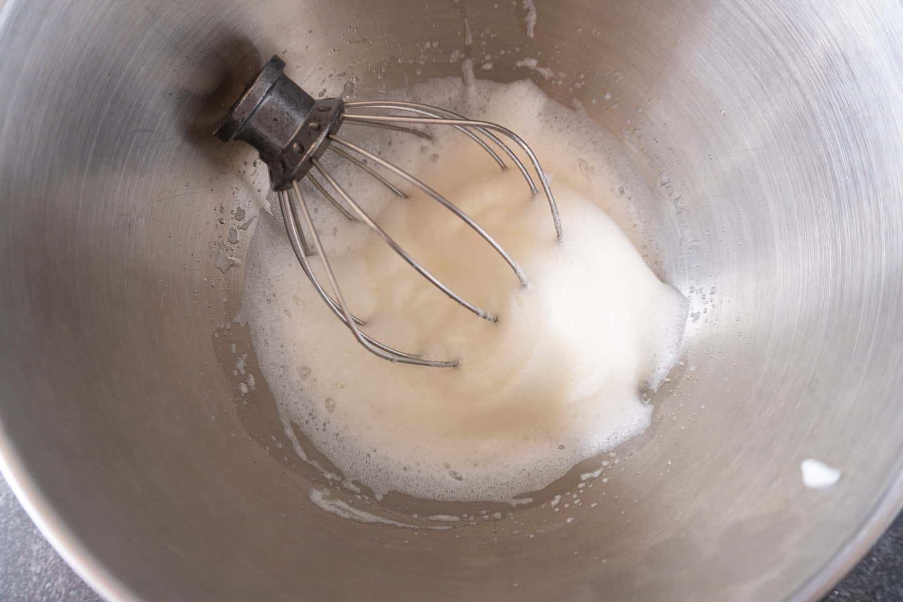 Egg whites whisked to a foamy consistency via a stand mixer whisk.