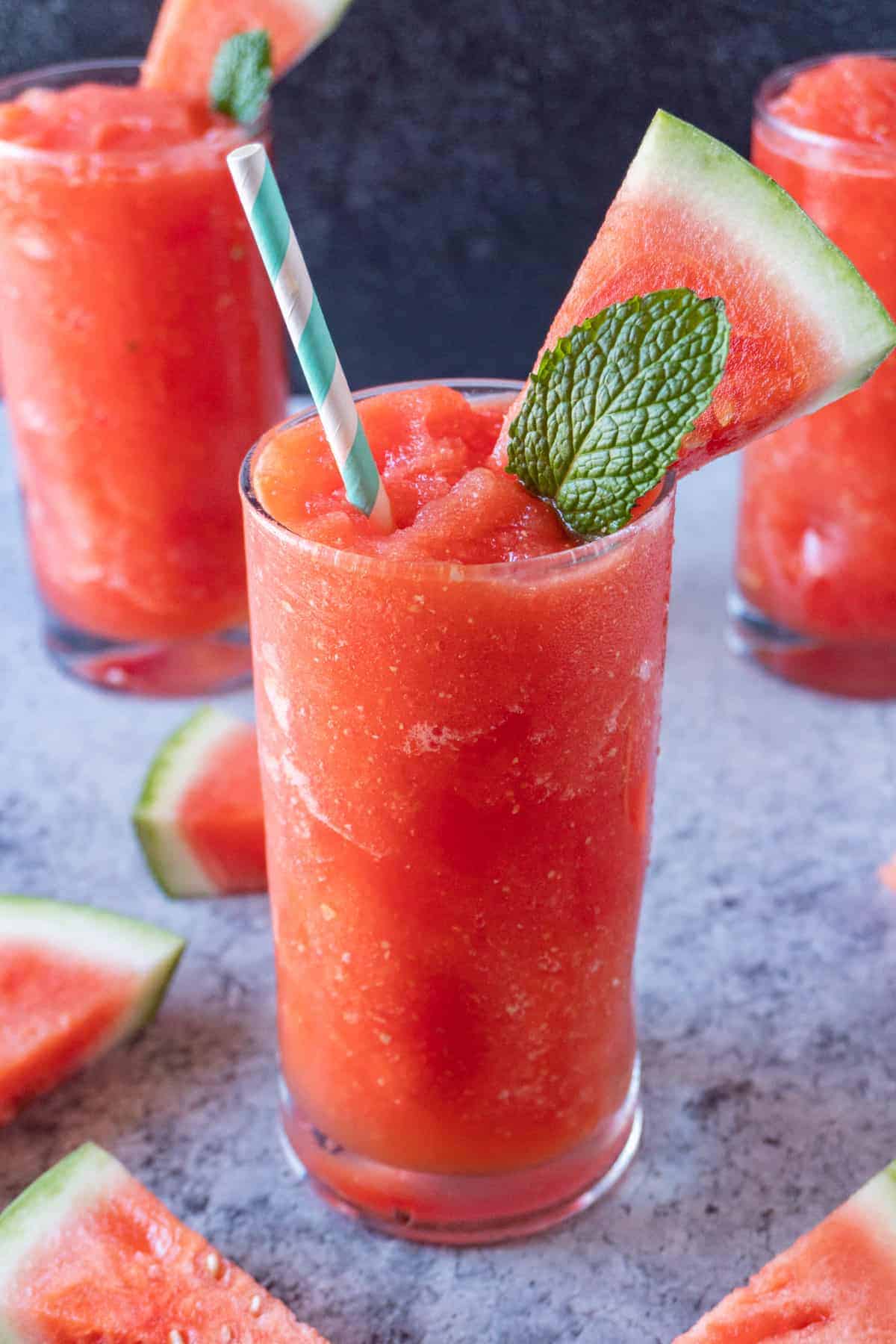 Watermelon Slushie in cup with watermelon slice and mint leaf sticking out