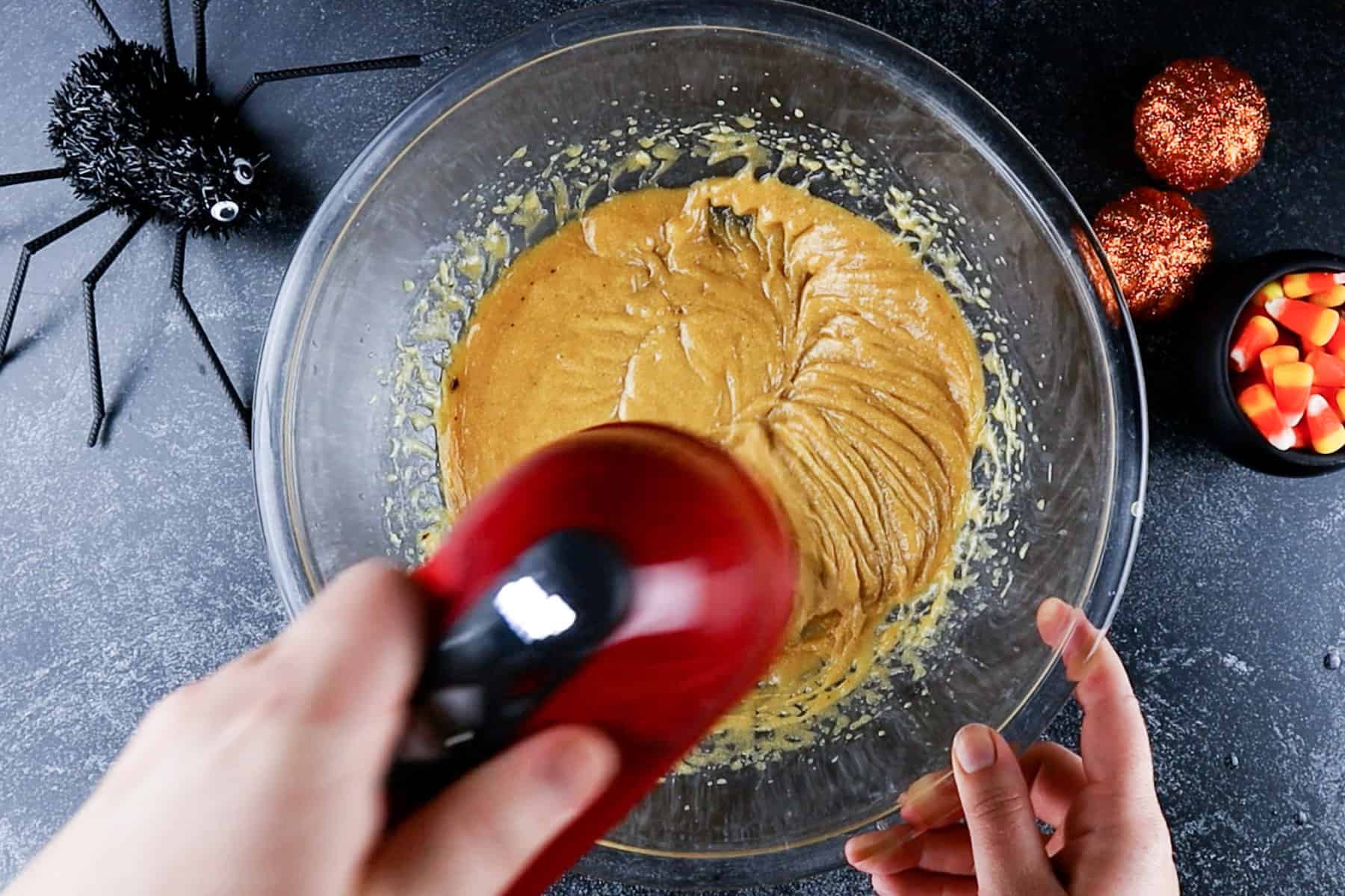 wet ingredients mixed with hand mixer in glass bowl.