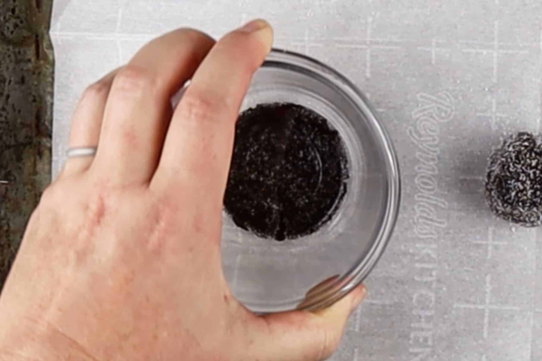 Flattening rolled cookie dough balls with the bottom of small bowl.