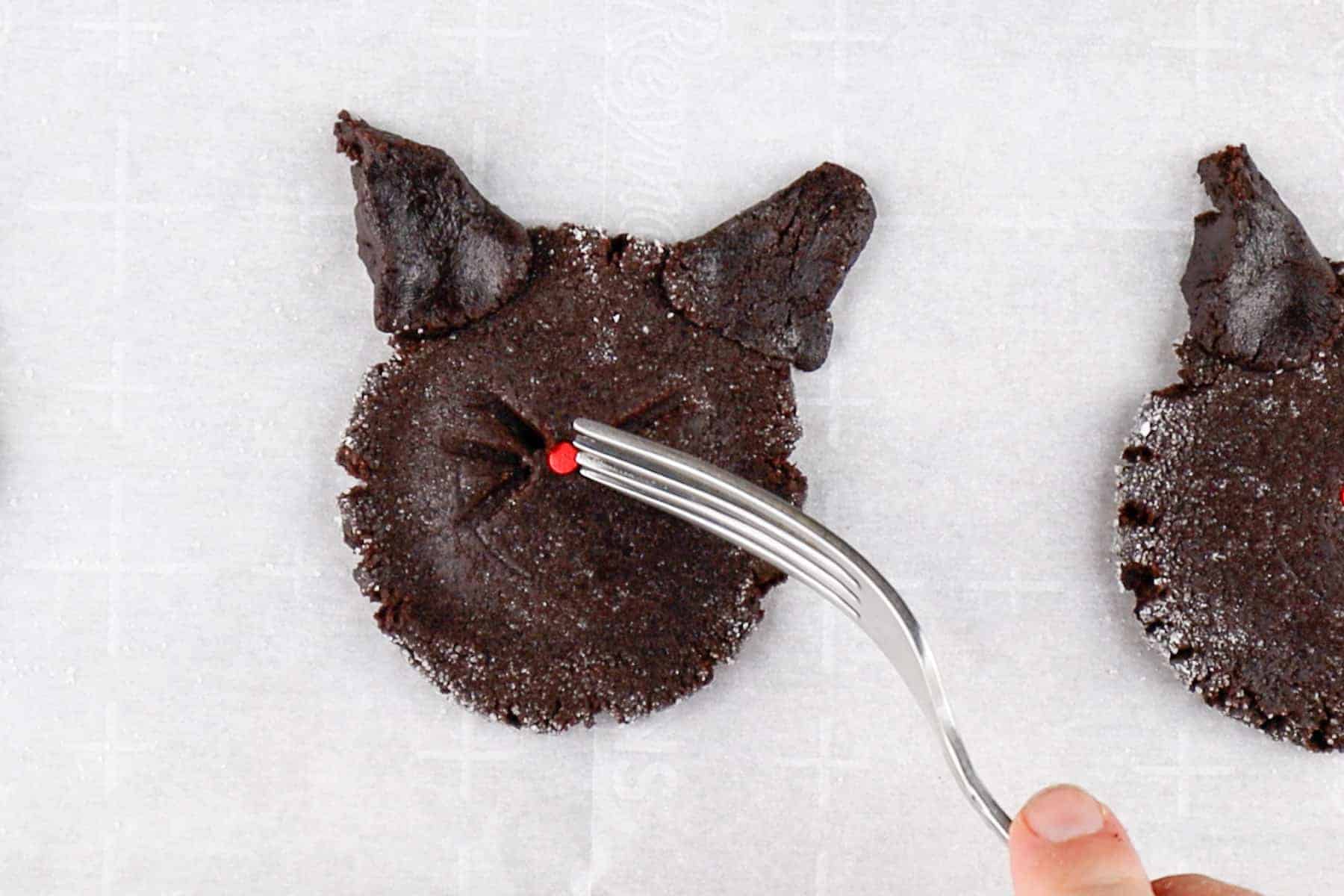 Making whisker indents with a fork on a flattened cookie dough round.