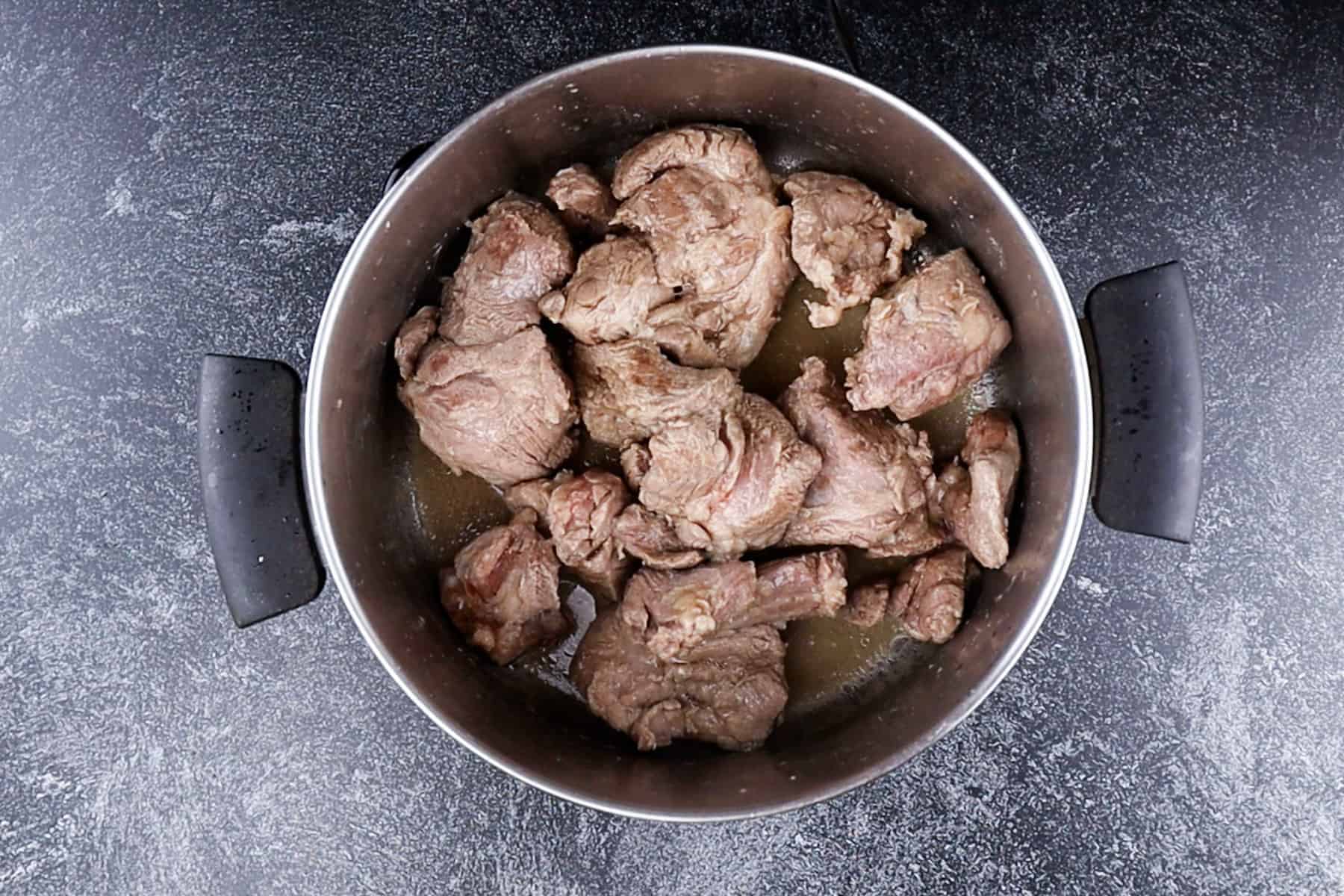 Browned pork butt pieces in pot.