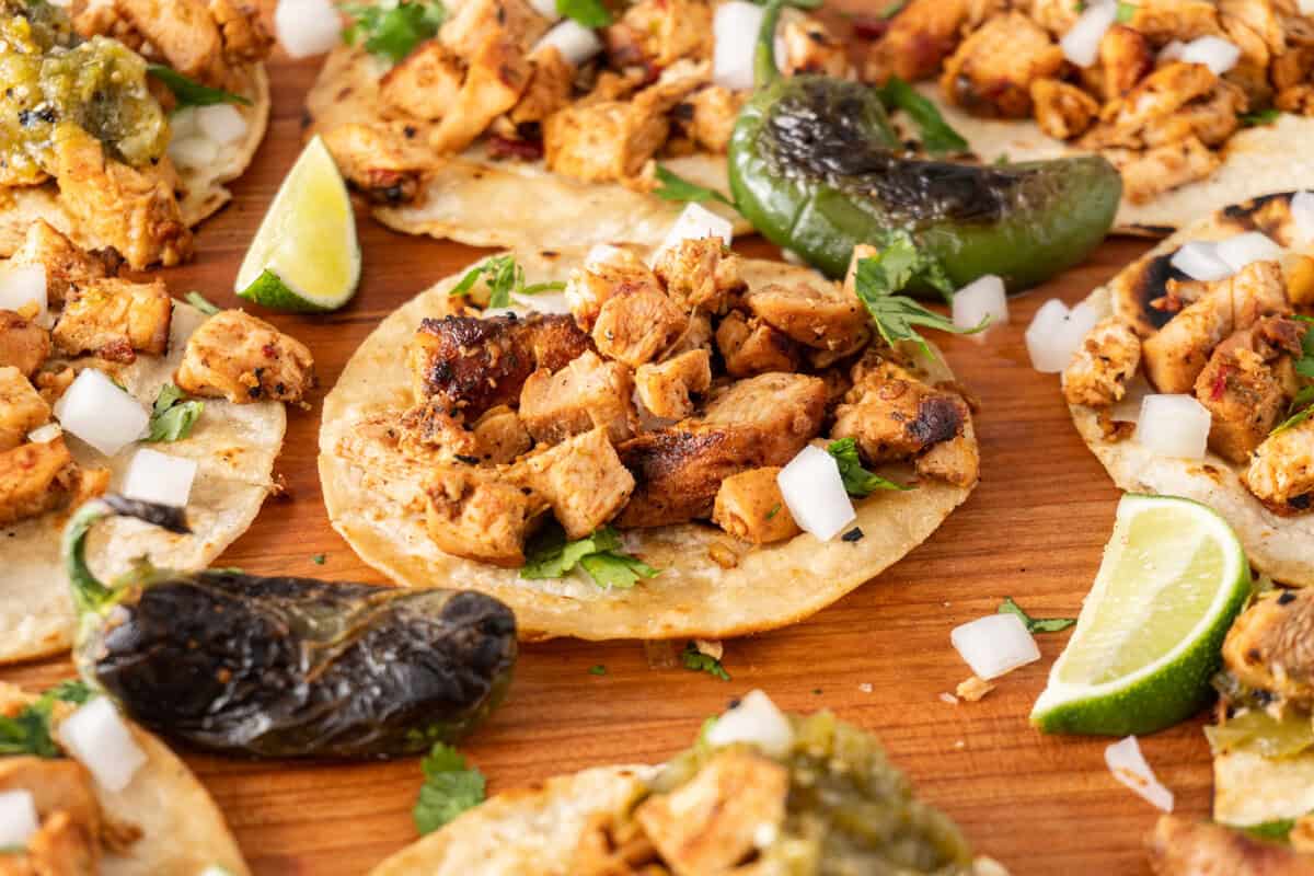chicken street taco on cutting board with lime wedges and charred jalapenos.