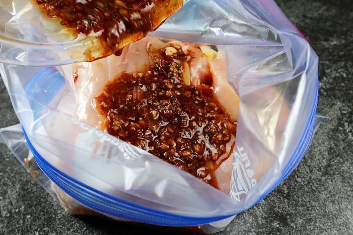 adding marinade to chicken in a bag.