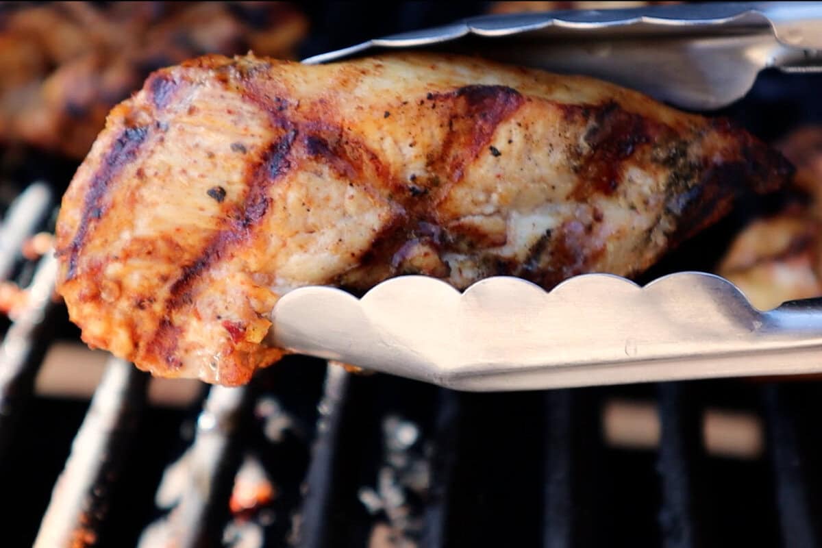 grilled chicken held by tongs.
