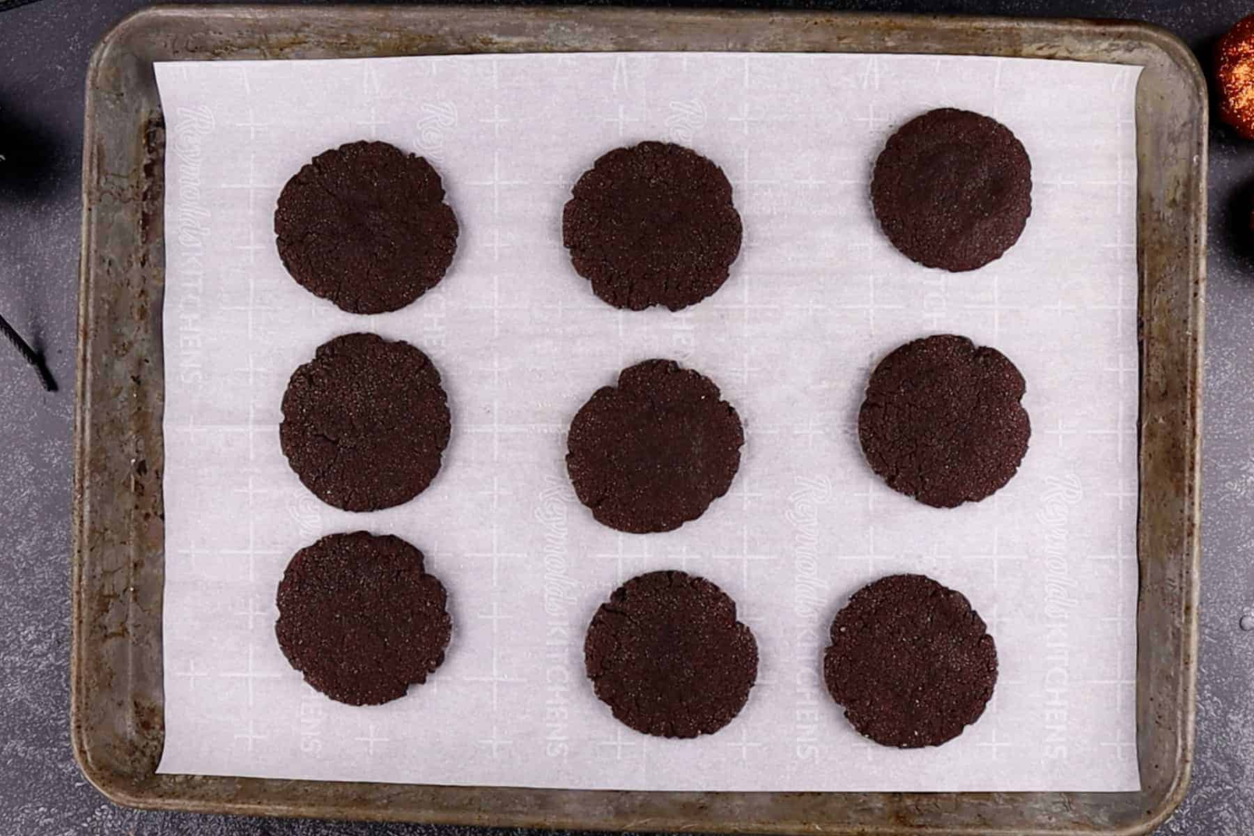 Chocolate Sugar Cookies baked and on a parchment-lined baking sheet.