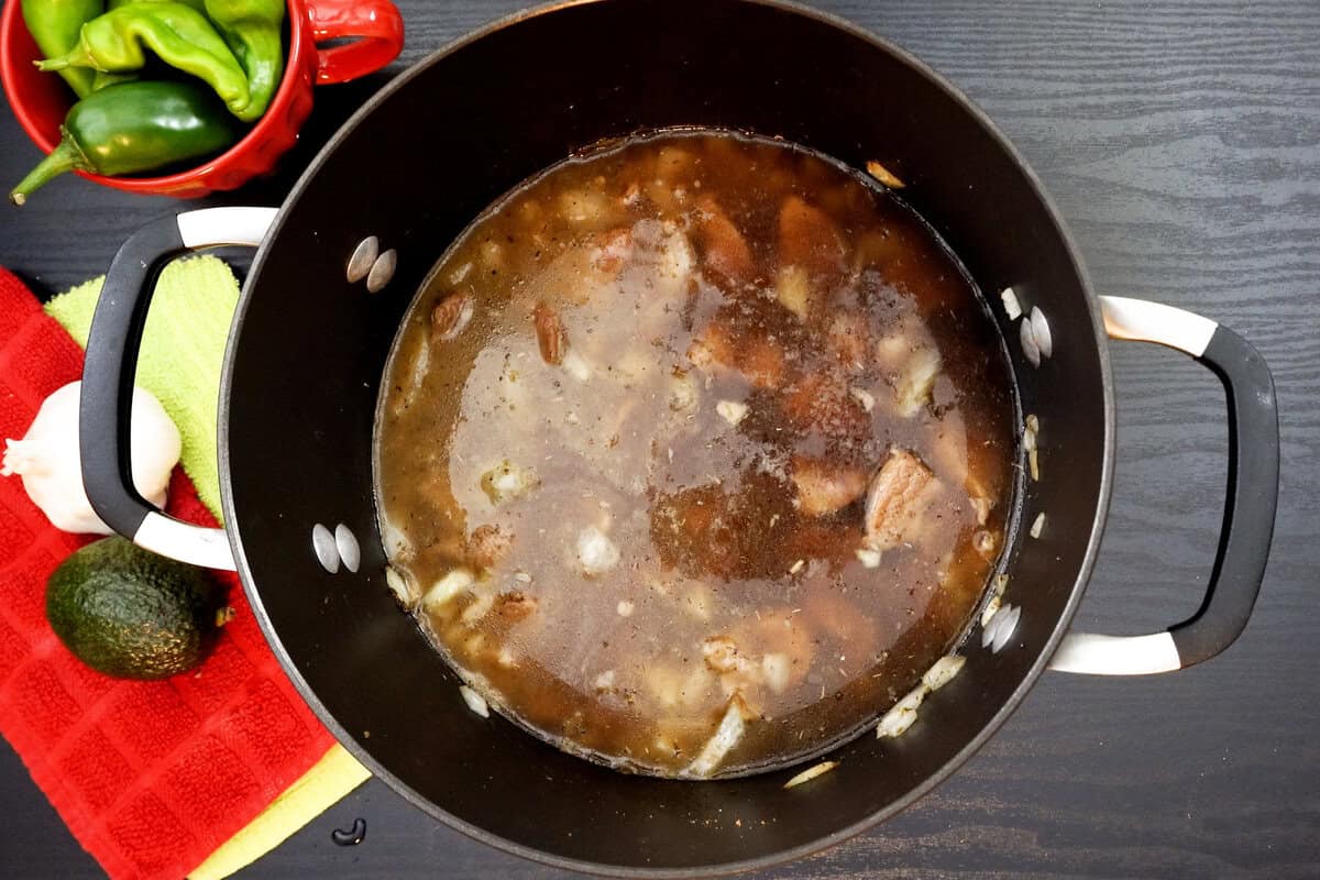 Broth, onions, spices, and meat in pot.