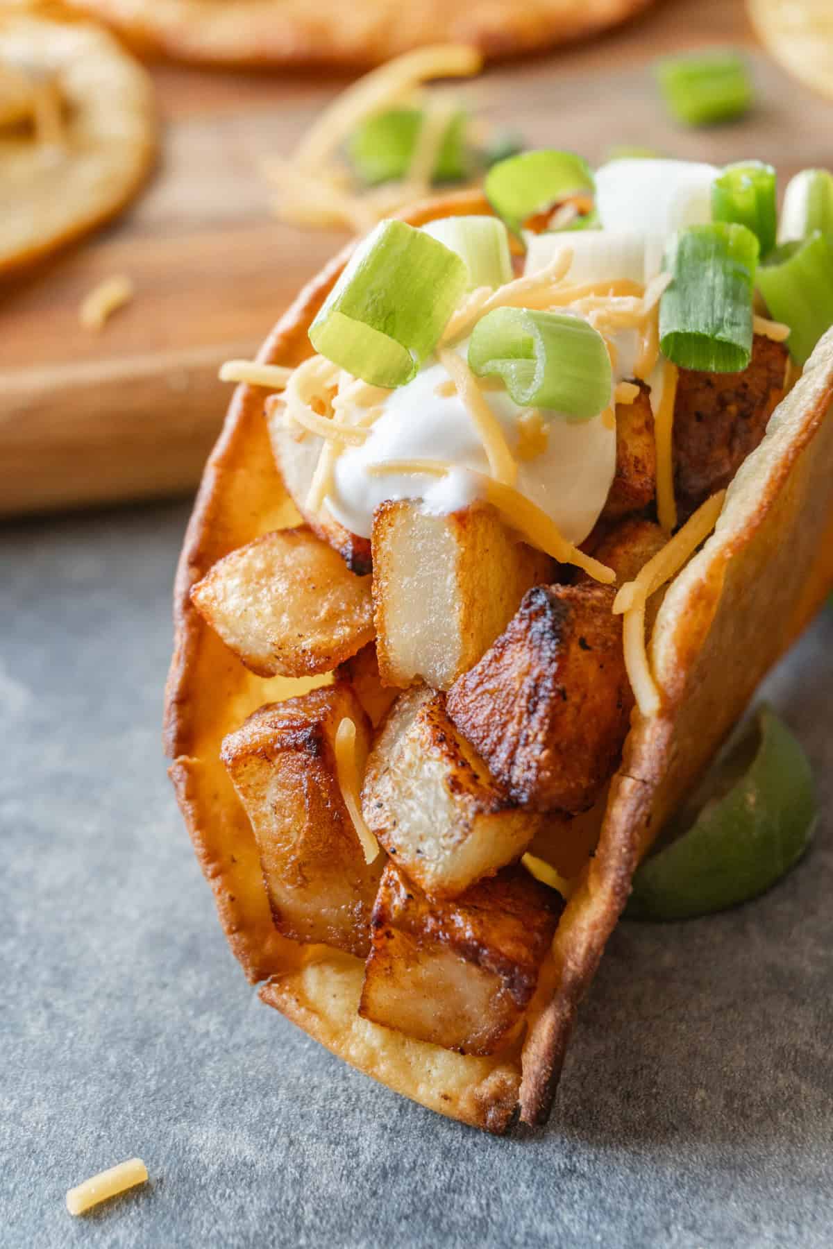 Potato taco in crispy corn tortilla topped with sour cream, cheese, and green onion.