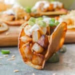 Potato taco in crispy corn tortilla topped with sour cream, cheese, and green onion.