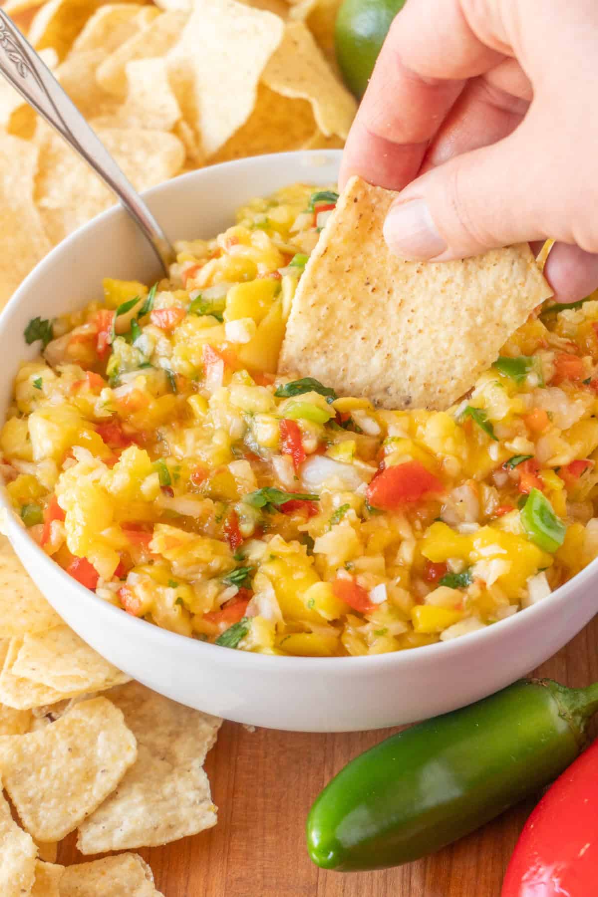 dipping a chip into pineapple mango salsa