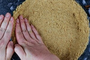 pressing the graham cracker crust into the the pie dish