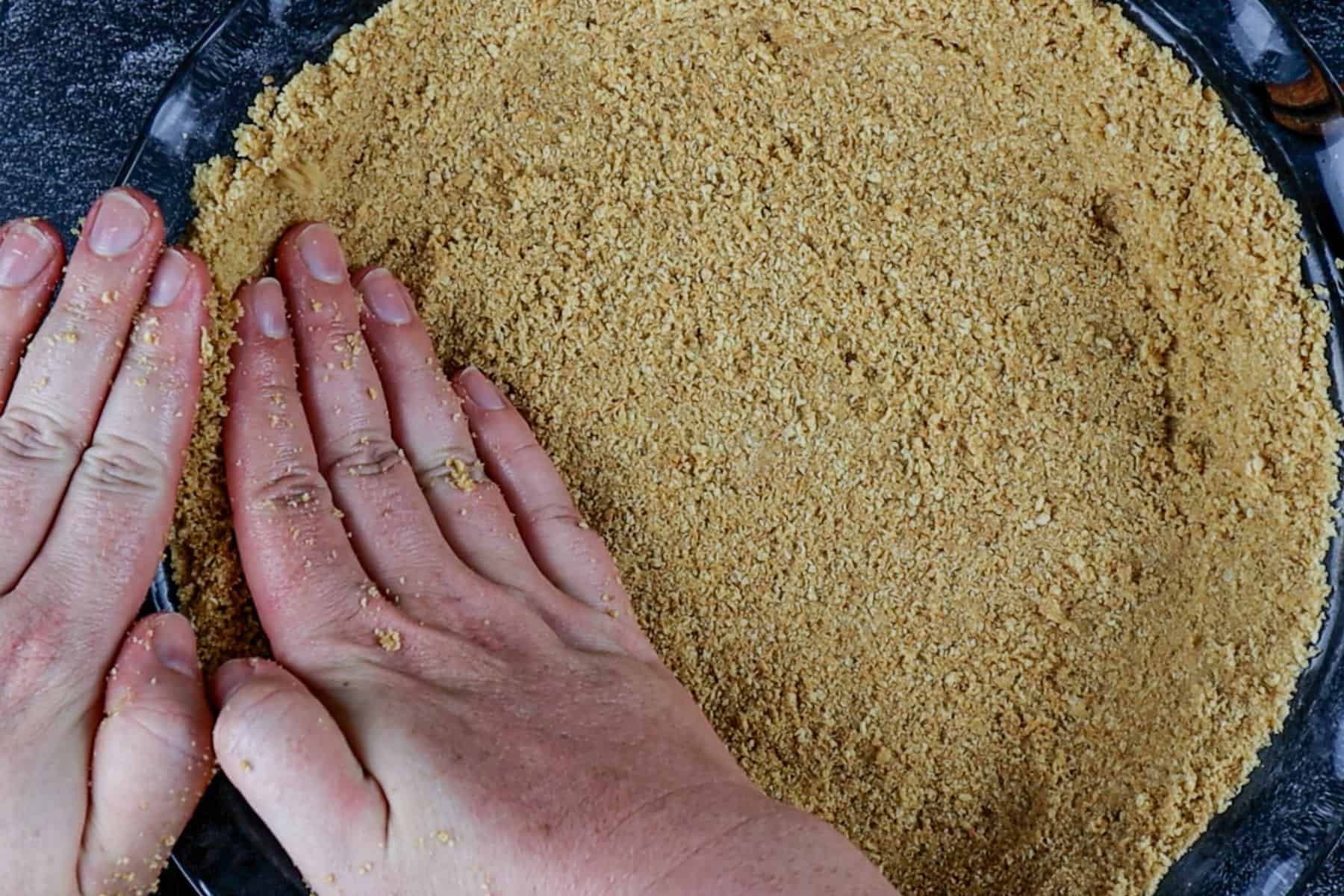 pressing the graham cracker crust into the the pie dish.