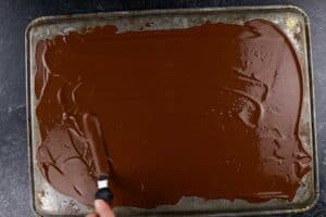 spreading out the melted chocolate on cookie sheet