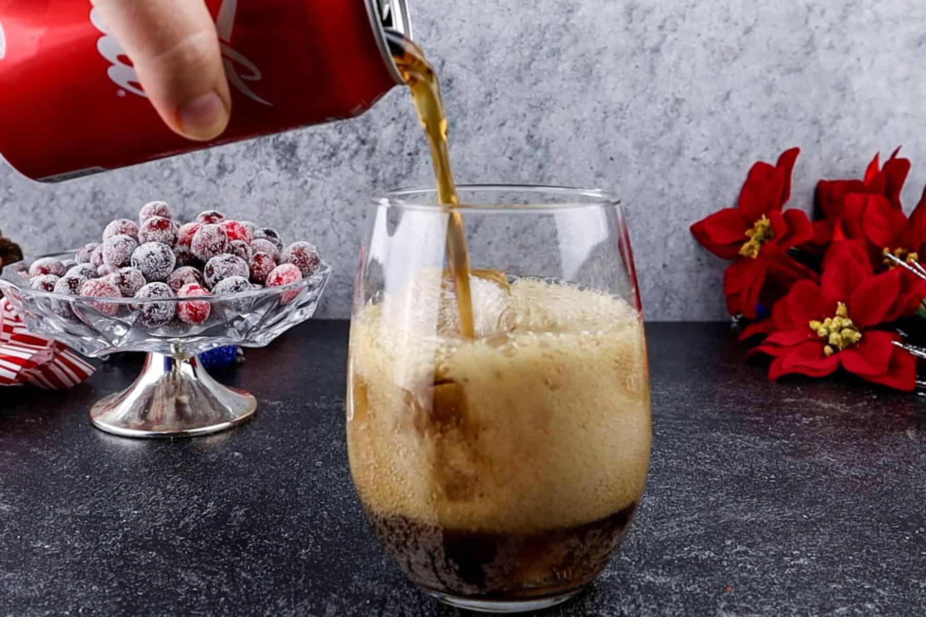 Adding soda to a glass with ice in it.