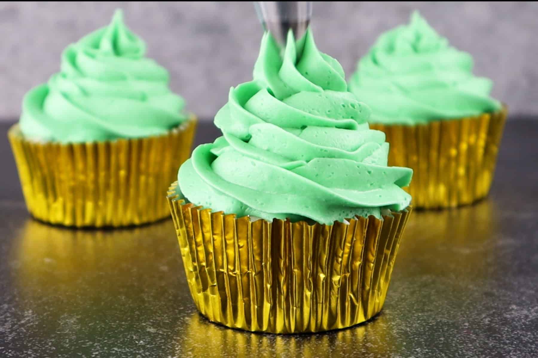 Finishing piping on the frosting tree, bringing the frosting around to a point in the center of the cupcake.