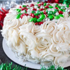 Easy holiday cake with piped on swirls and red and green decorations on top. Christmas decor in background. Featured image.