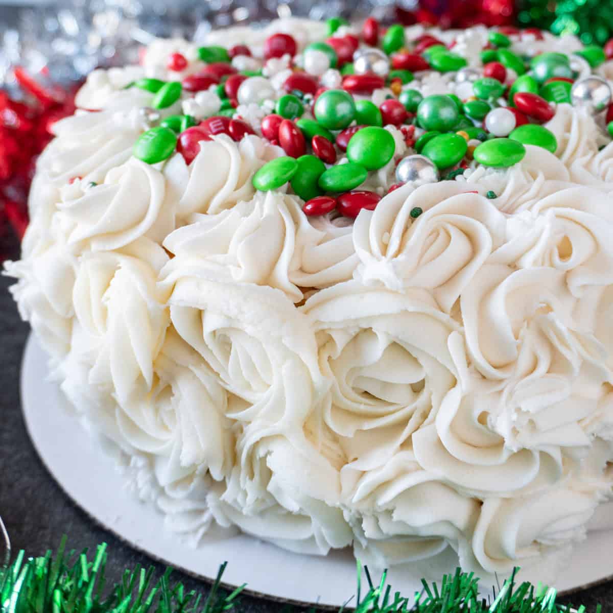 Easy holiday cake with piped on swirls and red and green decorations on top. Christmas decor in background. Featured image.