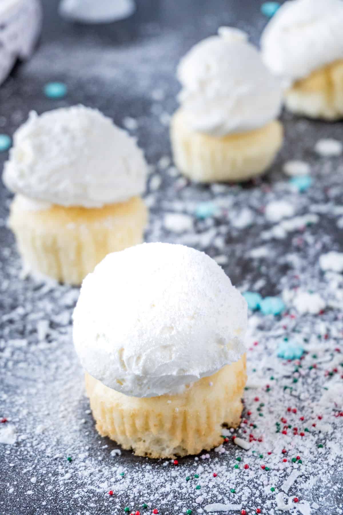 These fun and easy snowball cupcakes are perfect for the holiday season! Delicious buttercream on a perfect cupcake- all made to look like snowballs! snowball cupcake with powdered sugar sprinkled on top