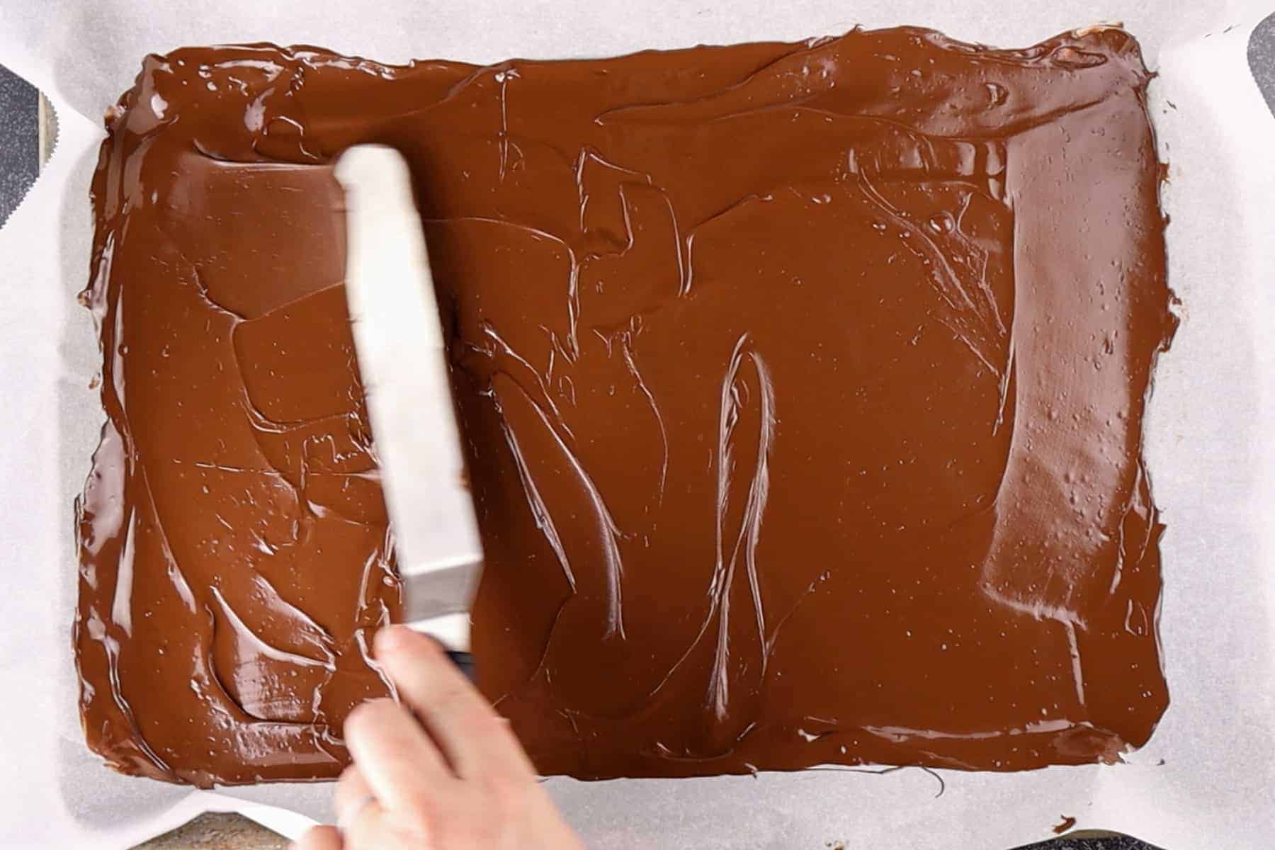 spreading melted chocolate onto a baking sheet.