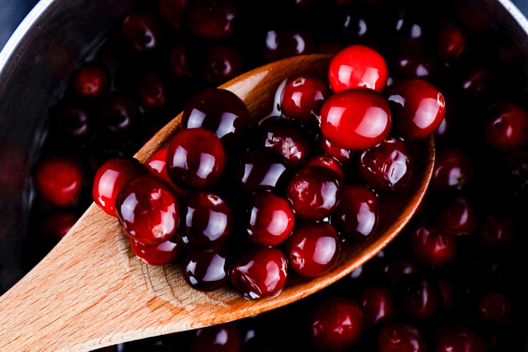 coated cranberries in sugar syrup on wooden spoon