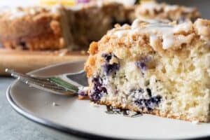 Blueberry Coffee Cake, An easy and delicious blueberry coffee cake that is perfect year-round! Topped with lots of crumb topping and a yummy glaze- you can’t go wrong with this blueberry coffee cake! #coffeecake #bisquick #homemade #blueberry #recipes #cinnamon #easy #atablefullofjoy