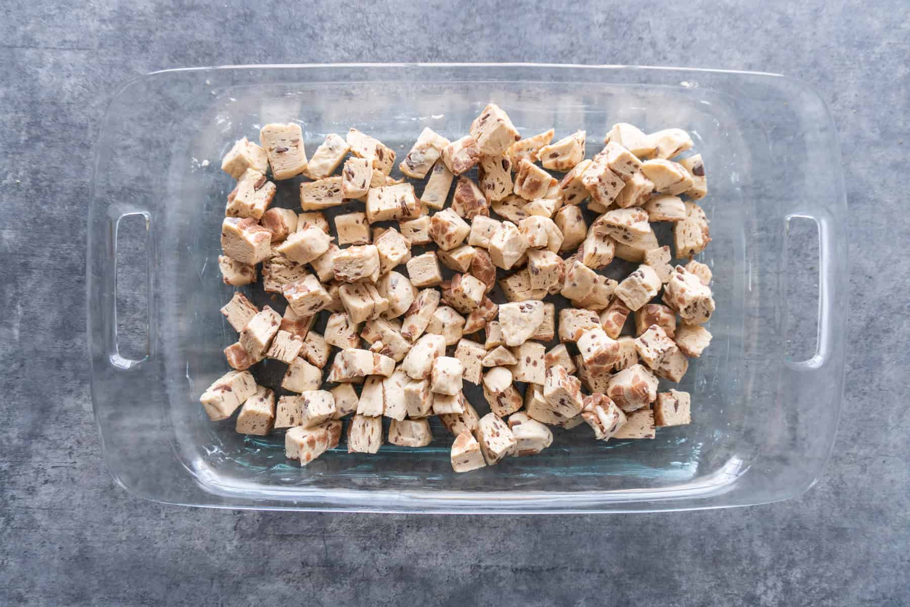 Cut up cinnamon rolls in a clear casserole dish.