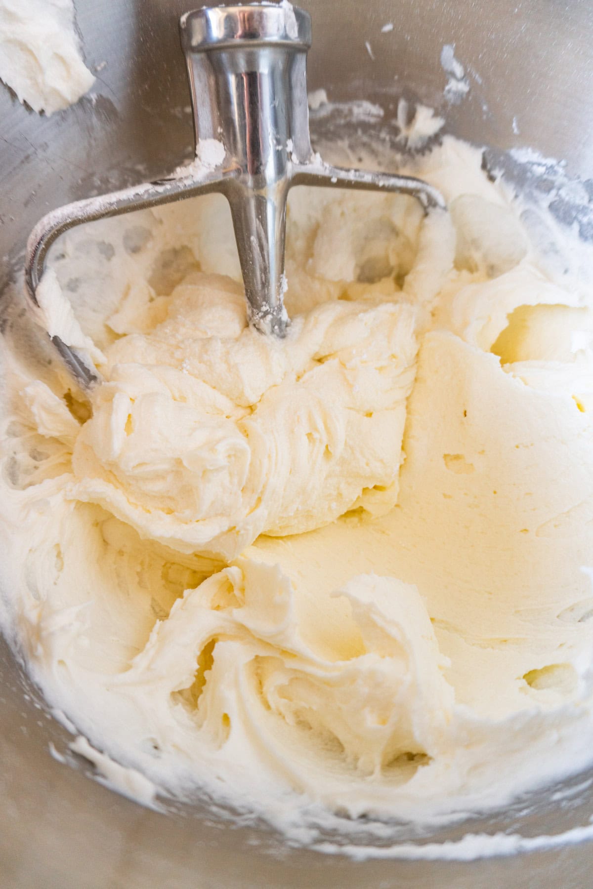 butter, sugar, and heavy cream mixed in metal mixing bowl.