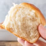 holding a soft dinner roll showing tender crumb featured image.